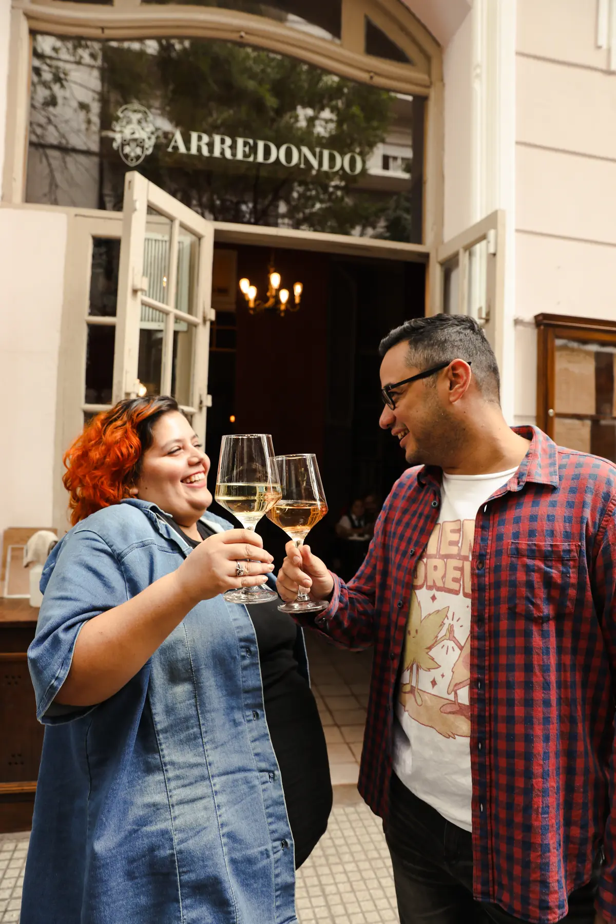 Dos personas brindando frente a la entrada de Arredondo